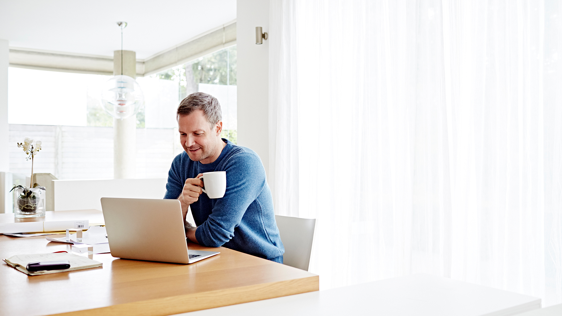 Image of a man drinking coffee while working